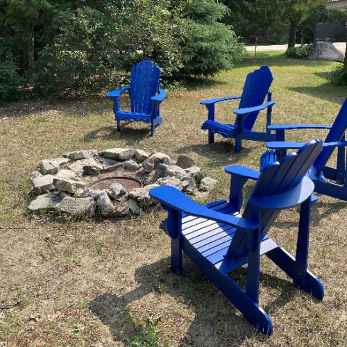 Gather around in the vibrant blue Adirondack chairs for an evening of warmth, laughter, and camaraderie under the open sky.