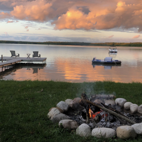 Sunset serenity at Cameron Lakehouse: unwind by the fire pit, soak in the tranquil lake views, and enjoy lakeside leisure with our private dock and floating trampoline. Your perfect escape into nature awaits.