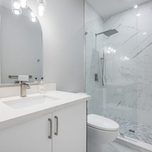 Third full bathroom with rainfall shower. Illuminate your morning and evening routines with well-placed vanity lighting, ensuring optimal visibility for grooming tasks. The combination of natural light and strategically positioned artificial lighting creates a bright and inviting atmosphere.