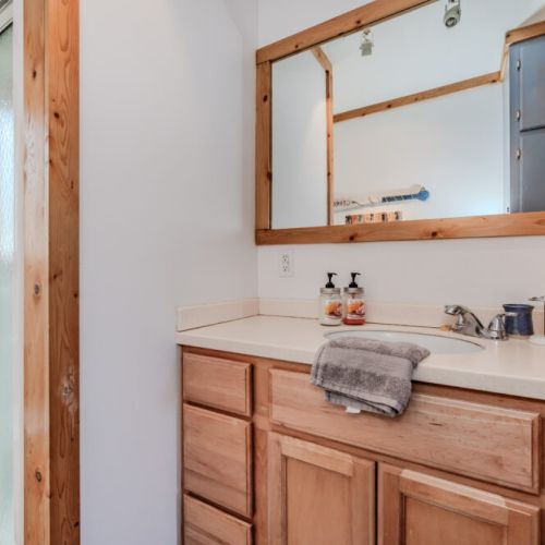 Updated ensuite bathroom with a spacious walk-in shower, wood accents, and cozy cottage charm, perfect for freshening up after outdoor adventures.