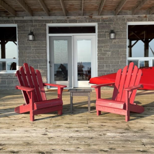 Relax in vibrant red Adirondack chairs on the spacious deck, with easy access to water activities and beautiful surroundings.