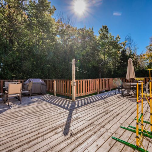 The large deck offers plenty of seating for dining or relaxing, surrounded by serene greenery and enhanced with soft string lights.
