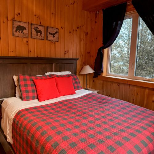 Sleep soundly in a rustic bedroom featuring cozy plaid bedding and natural wood finishes—ideal for peaceful retreats and nature vacations.