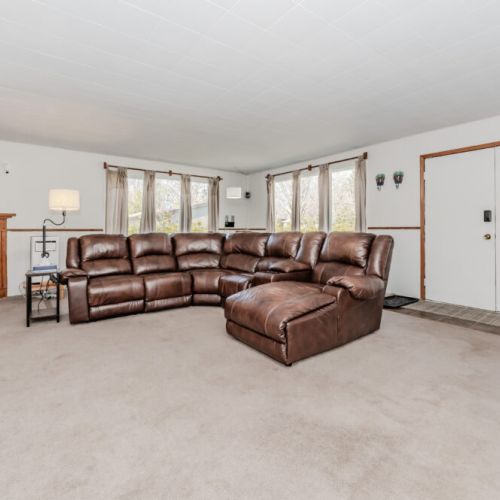 Comfort meets charm in this welcoming living room with a full sectional sofa and wood fireplace—unwind after a day exploring cottage country.