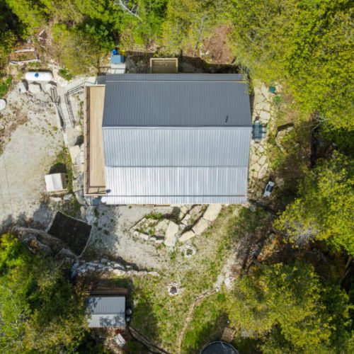 Hidden in plain sight. Clear metal roof, stone patios, and completely enveloped by the green canopy.