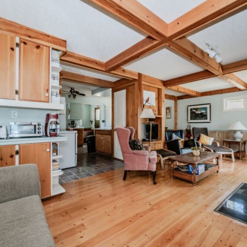 The heart of Beeshore, the living room features a warm fireplace, comfortable seating, and rustic wooden interiors. Perfect for gatherings, this space exudes a welcoming ambiance for relaxation and enjoyment.