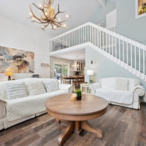 Stylish great room with soaring ceilings, loft overlook, and statement chandelier