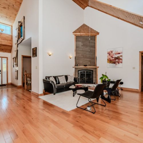 Cozy up by the wood-burning fireplace in the airy, open-concept living room with soaring ceilings.