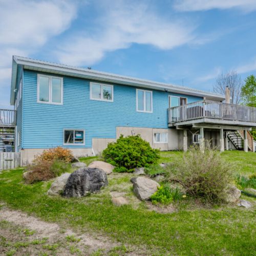 Scenic backyard with rock features and grassy space—ideal for kids to play, evening bonfires, or lounging after a day by the lake.