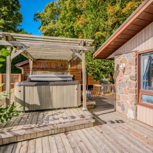 Unwind in the private hot tub under a charming pergola, offering both shade and views of the surrounding natural beauty.
