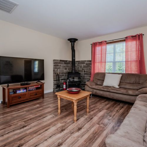 Unwind in the cozy living room, complete with plush seating, a large smart TV for streaming, and a wood-burning stove for extra warmth and ambiance.