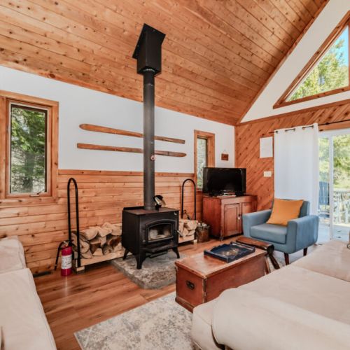Cozy living room with wood stove and soaring ceilings, perfect for relaxing after a day of lake adventures at your charming cottage rental.