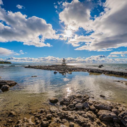 A stunning lakeside view featuring the crystal-clear waters of Lake Huron and a charming inukshuk. The perfect spot to marvel at spectacular sunsets and connect with nature.