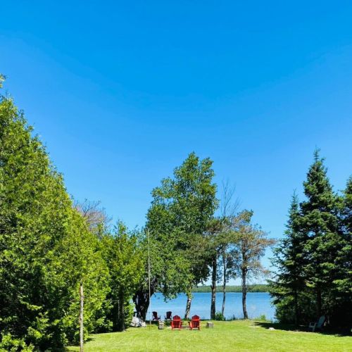Soak up summer on a wide grassy lawn with cozy firepit seating and endless lake views—perfect for family fun and outdoor relaxation.