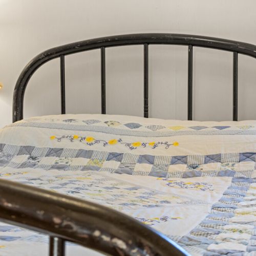 Cozy bedding and classic farmhouse character create a comfortable retreat for a restful night.
