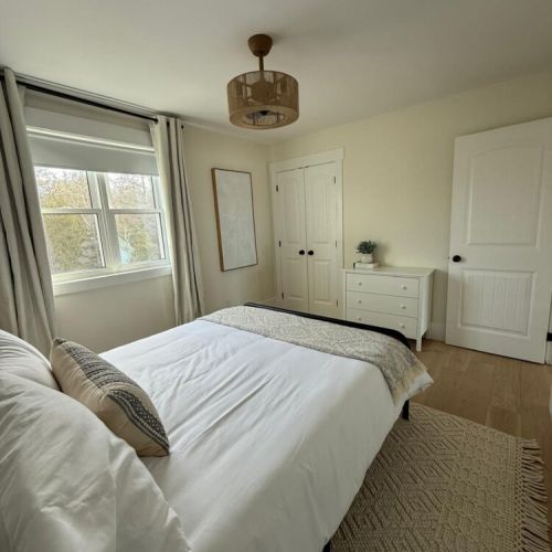Cozy up in this sun-filled queen bedroom, featuring modern coastal décor and soft linens for a restful night’s sleep.