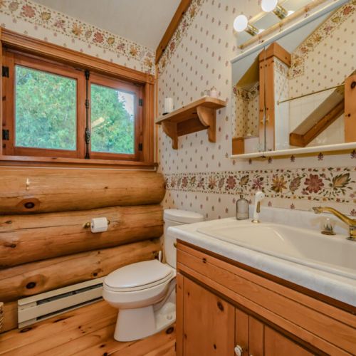 This unique bathroom blends rustic charm with functionality, showcasing log accents, warm wood cabinetry, and a thoughtfully designed layout for ultimate comfort.
