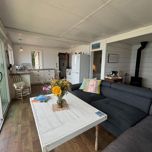 Open-concept lounge with large windows, comfy seating, and direct access to the kitchen.
