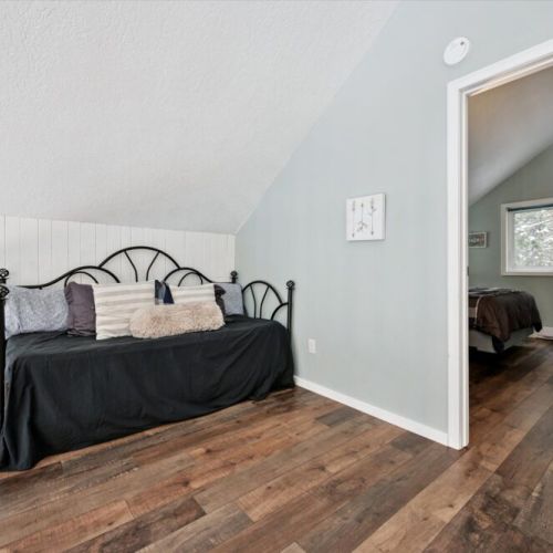Cozy upstairs bedroom with queen bed, warm wood floors, and peaceful sloped ceilings