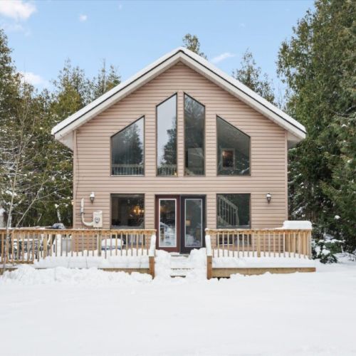 Striking A-frame style front exterior with wall-to-wall windows and spacious wraparound deck