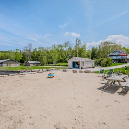 The private sandy beachfront is perfect for family fun and relaxation. A picnic table and children's play area invite guests to enjoy the sun and sand, while the surrounding greenery provides a peaceful backdrop.