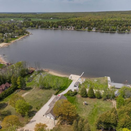 An aerial perspective captures the expansive property and its prime location along the lake. The clear view of the beach, dock, and surrounding homes showcases the peaceful and picturesque setting of Jack's Retreat.