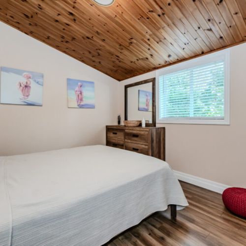 A charming bedroom with a rustic, peaceful vibe, perfect for a restful night. The wood-paneled ceiling and stylish decor add a cozy touch.