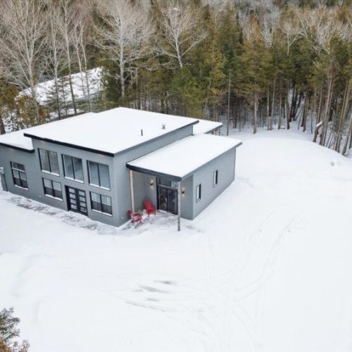Aerial winter view of the home tucked into a peaceful forest setting for total privacy.