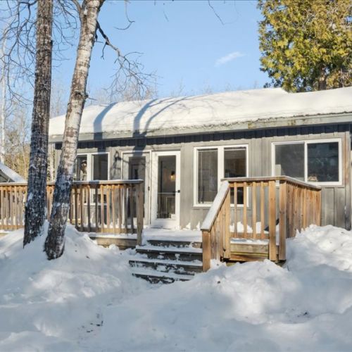 Exterior of the shared cabin space set among the trees in a beautiful winter landscape. A charming bonus retreat to complement your stay at Lofty Dreams.