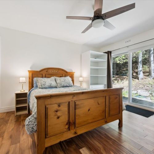 The comfortable primary bedroom offers a peaceful retreat with forest views and direct outdoor access.