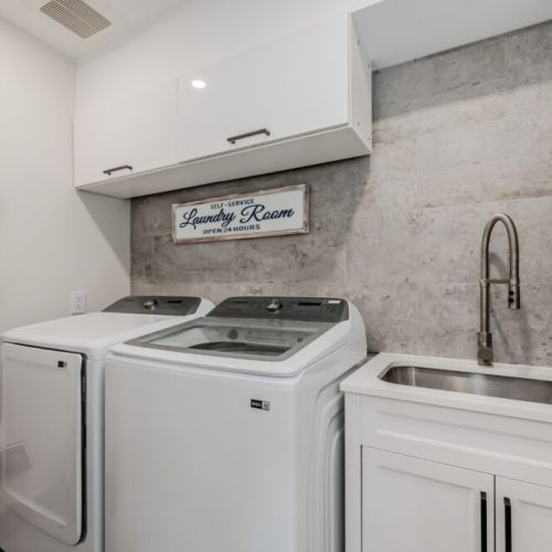 The laundry room is fully equipped with a washer, dryer, and utility sink. Clean, organized, and practical, it ensures that guests have everything they need for a comfortable stay.