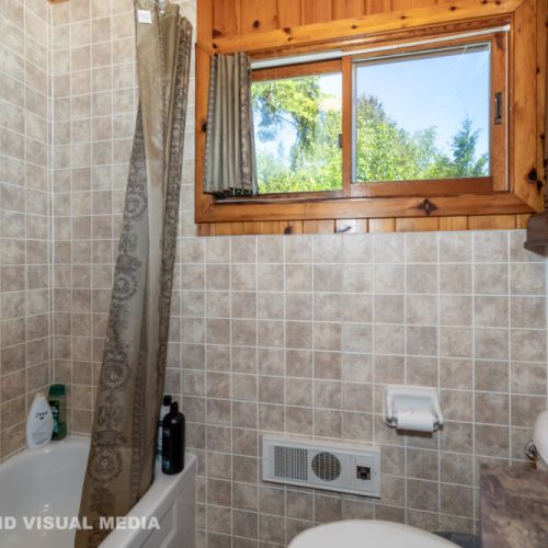 Clean and functional bathroom with a bright window and full tub/shower.