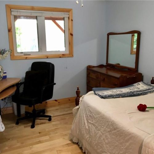 A bright guest room with a desk and dresser provides a relaxing space for rest or a quiet moment indoors.