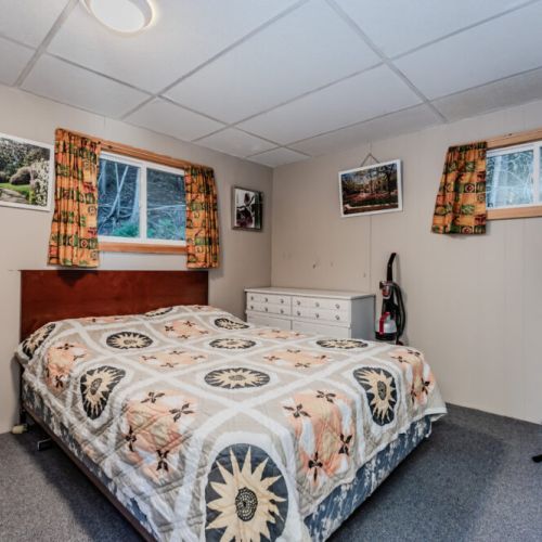 The bedroom has a cozy, rustic vibe with a double bed, dresser, and fan to keep cool on warm nights.