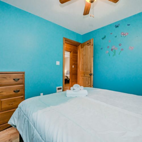 A bright and cheerful bedroom, perfect for guests or children, with colorful décor and comfortable bedding. The room is equipped with a dresser and a spacious closet, ensuring guests have everything they need to feel at home. The vibrant walls and charming accents add a touch of fun to the space.