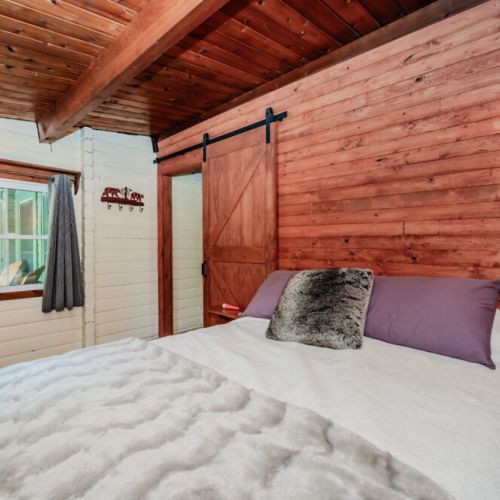 Retreat to this tranquil bedroom, featuring soft linens, barn-style door, and rustic charm—ideal for romantic getaways, weekend escapes, or serene nature stays.