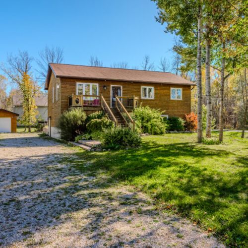 The landscape features neatly trimmed shrubs and bright tulips, creating a serene and inviting atmosphere with plenty of parking space for guests.