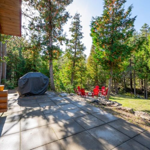 Step outside to the charming patio area, complete with bright red chairs, invites guests to savor peaceful moments in the fresh Tobermory air.