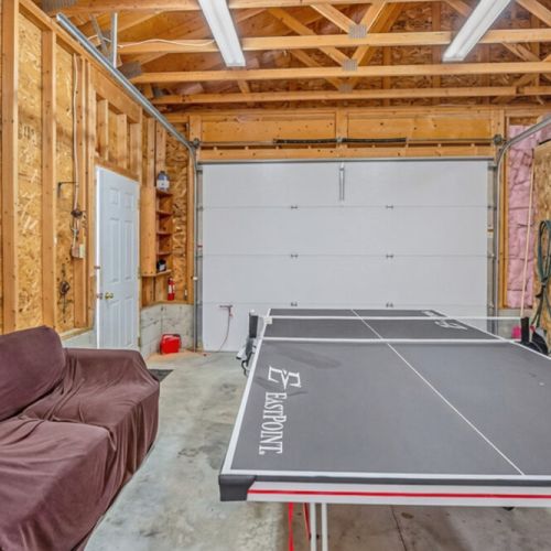 Enjoy indoor recreation in a spacious games garage featuring ping pong and lounge seating. A perfect all-season amenity for families, groups, and relaxed cottage vacations.