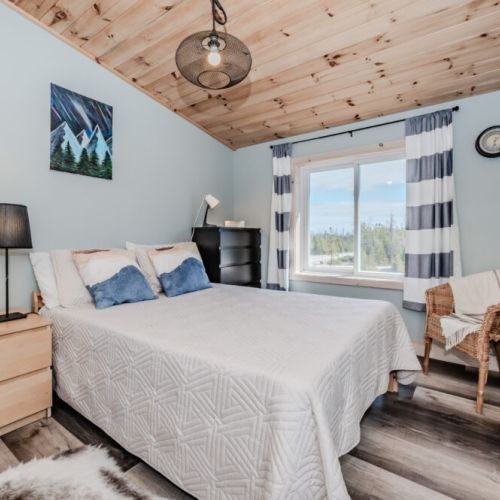 Wake up to forest views in a sunlit bedroom with rustic touches—comfort meets serenity in this perfect Bruce Peninsula getaway spot.