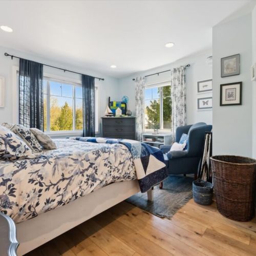 Wake up to sunshine and nature in this spacious bedroom, complete with comfortable seating and large windows overlooking the property.