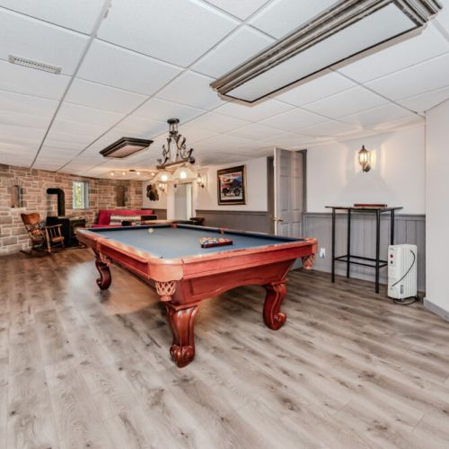 🎱 **Entertainment Lounge**  
Unwind in the ultimate game room featuring a classic pool table, cozy wood stove, TV lounge, and rustic charm—perfect for relaxing evenings on your lakeside vacation.
