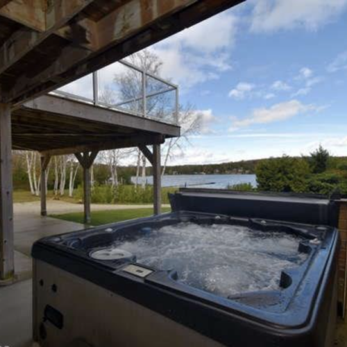 Unwind in Luxury: Jack's Retreat's hot tub area, a secluded spot for relaxation amidst the gentle sounds of nature and breathtaking views of the waterfront.