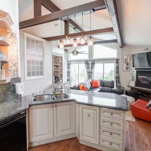 Open-concept kitchen and living space with vaulted ceilings, granite counters, and a welcoming breakfast bar.