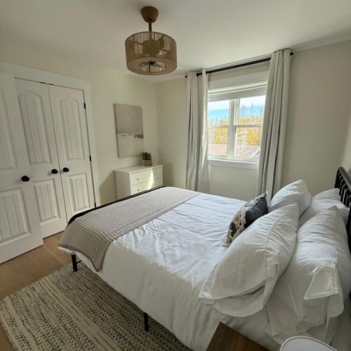 Cozy up in this sun-filled queen bedroom, featuring modern coastal décor and soft linens for a restful night’s sleep.