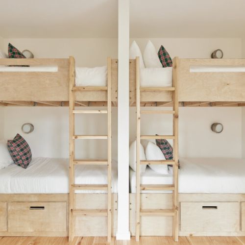 Two sets of bunk beds with plaid pillows, designed for a comfortable group stay.