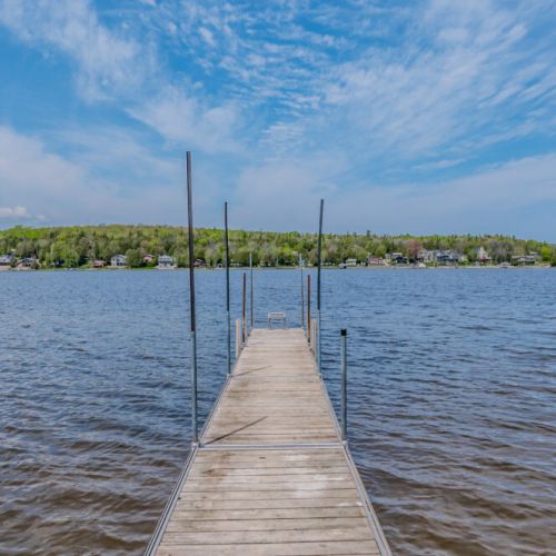 The long dock extends out into the serene lake, offering a perfect spot for fishing, swimming, or simply taking in the beautiful water views. The tranquil setting is ideal for a quiet escape.