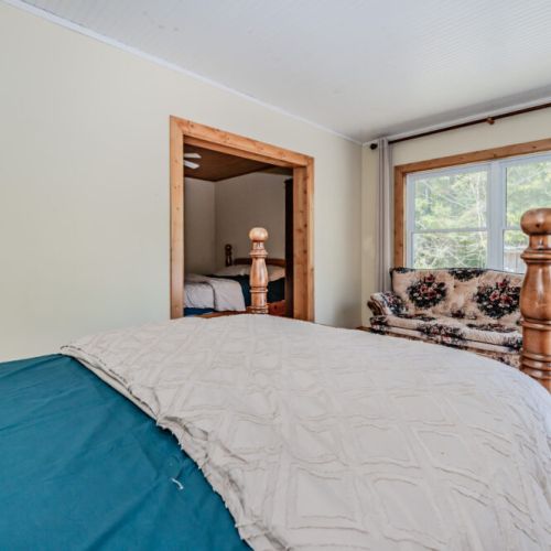 Spacious bedroom with double beds and large windows, ideal for families or friends seeking a tranquil stay near the woods.