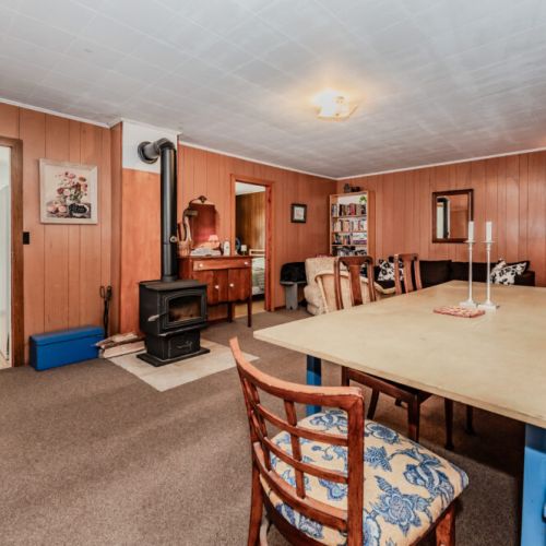 Spacious rustic lounge with wood stove, dining space, and cozy seating—perfect for gathering with family and friends on your countryside escape.