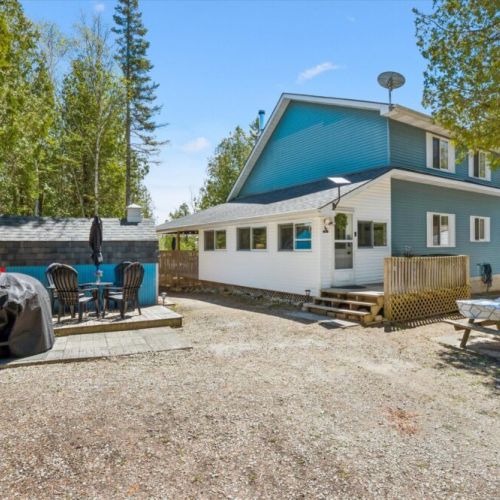 Rear exterior view of the cottage featuring outdoor dining, hot tub area, and easy access to the waterfront.
